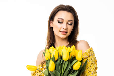 Young pretty woman with bouquet of yellow tulips on white backgroundの写真素材