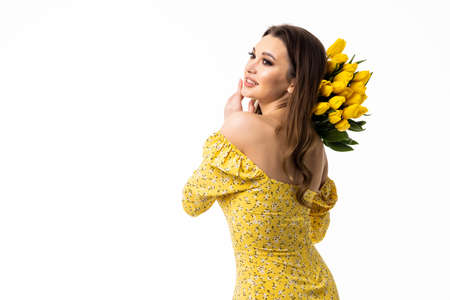 Beautiful woman in the dress with flowers tulips in hands on a light backgroundの写真素材