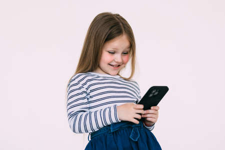 little girl holding a smart phone against white backgroundの写真素材