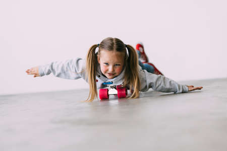 Happy child is riding lying a skateboard like flying indoor