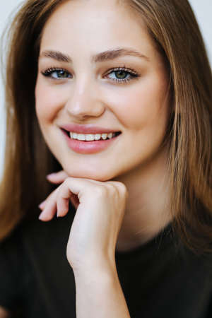 Front view portrait of a happy teen girl sitting on a couch in the living room at homeの写真素材