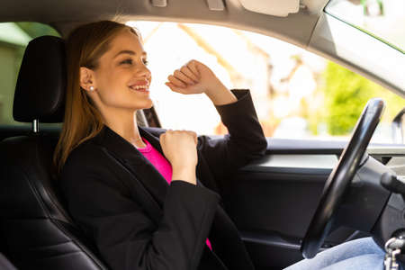 Beautiful girl is dancing and smiling while driving a carの写真素材