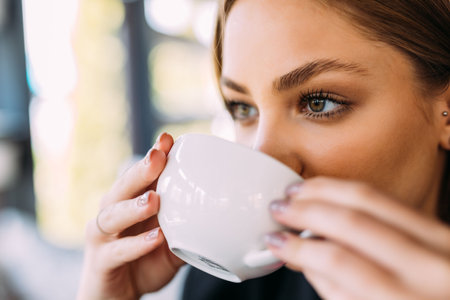 portrait of young woman drinking coffee at table with notebook in cafeの写真素材