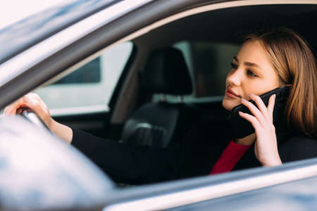 businesswoman driving car and talking on cell phone concentrating on the road