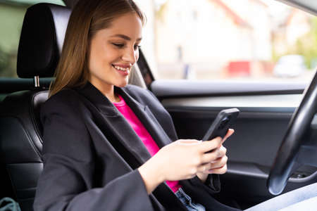 woman sitting in car use mobile phone texting while driving dangerousの写真素材