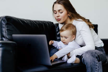 smiling freelancer pointing at laptop while holding little son