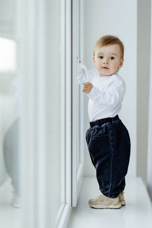 Portrait of white Caucasian child boy at home looking out of window outside.