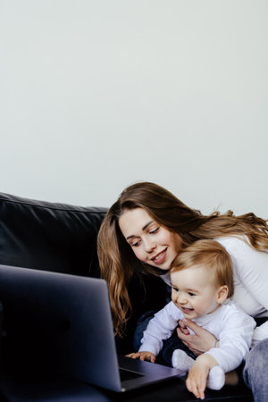 smiling freelancer pointing at laptop while holding little son