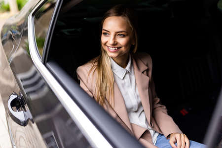 Young businesswoman listening to music on back seat of a carの写真素材