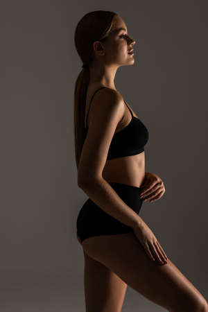 Muscular female perfect slim body in black lingerie isolated on gray backgroundの写真素材