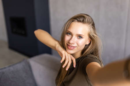 Picture of young amazing happy emotional pretty lady lies on sofa indoors. Looking camera make selfie.の写真素材