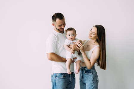 Full length portrait of a happy young family with their little son standing together isolated over white backgroundの写真素材