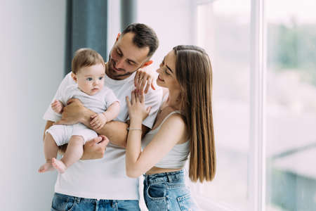 Woman and man holding a newborn. Mom, dad and baby. Portrait of smiling family with newborn on the...