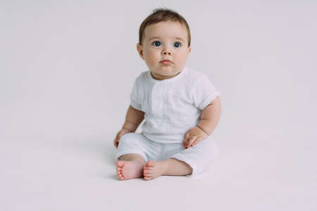 Young parents lying in bed, playing and looking at their cute little baby from above.の写真素材