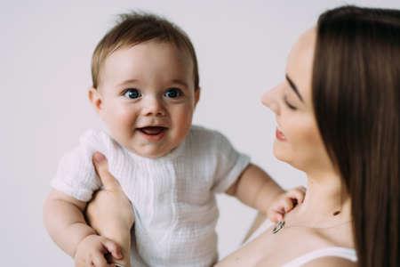 Happy smiling mother with baby having fun together on white background