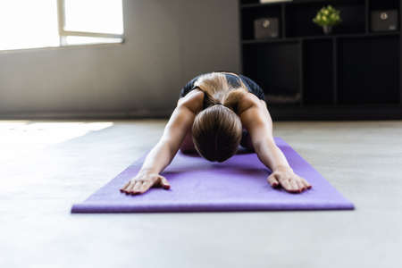 Fit woman making cobra pose on yoga mat, exercising in studio over panoramic windowの写真素材
