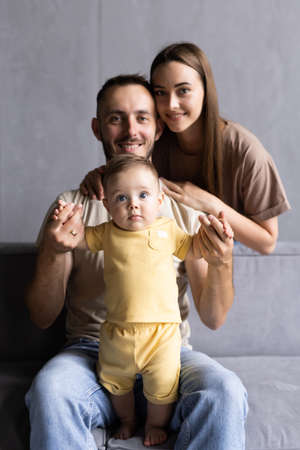 Parents and their son sit huddled in the living room and smilingの写真素材