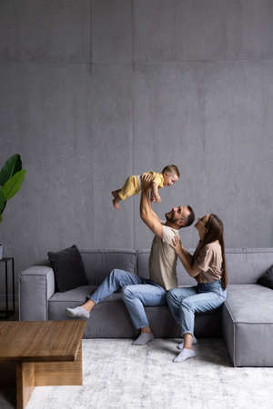 happy family mother father and kid having fun at home on the couchの写真素材