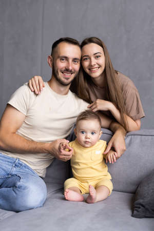 Cheerful family are spending funny time while sitting on sofa in room. happy parenting conceptの写真素材