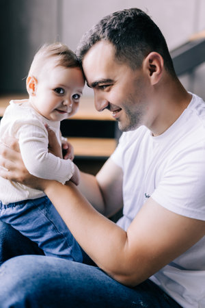 happy father playing with his baby daughter in the bright living room near the window. The concept of friendly family.の写真素材
