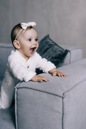 Cute newborn smiling baby on sofa. Infant girl sitting on special little baby furnitureの写真素材