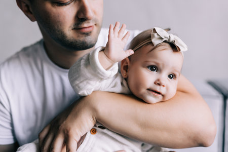 Happy father lying on sofa holding baby girl, playing, smiling. side view.の写真素材