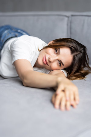 Tired woman lying on cozy couch take nap daydreaming in living roomの写真素材