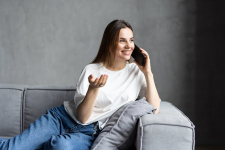 Attractive smiling woman talking on the phone at home. Technology, communication and cosiness...