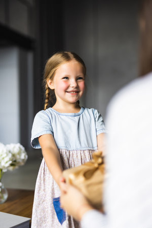 Child congratulating mom. Mum and daughter smiling and holding gift.の写真素材