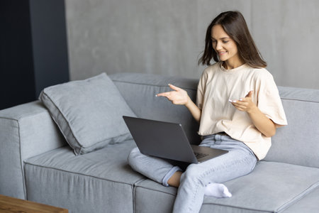 Young happy woman holding video call, gesturing hi to friends, relatives or parents. Attractive female blogger recording new video to followers. Smiling girl having online interview with employer.の写真素材