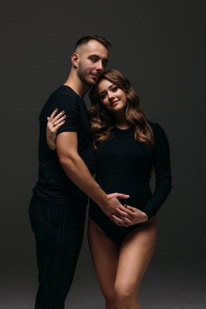 Handsome pregnant couple posing on dark background.の写真素材