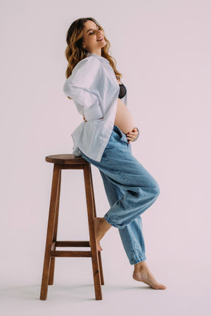 Pregnant woman sitting on a chair on a white background
