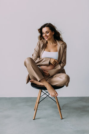 Pregnant woman sitting on a chair on a white backgroundの写真素材