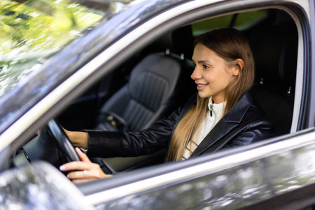 Confident and beautiful. Rear view of attractive young woman in casual wear looking over her shoulder while driving a carの写真素材