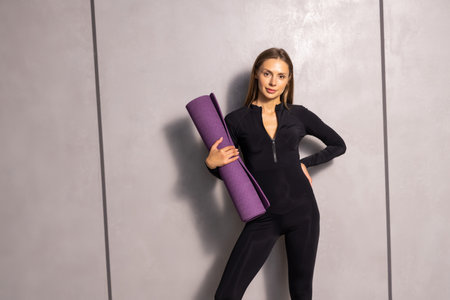 Full length shot of slim woman with fitness body, wears top, leggings and sneakers, holds exercise...