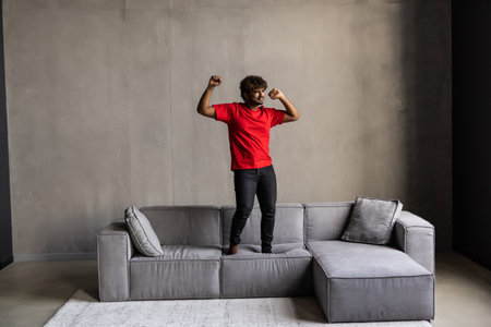 Cheerful man dancing on the couch in the living room. Shot at home