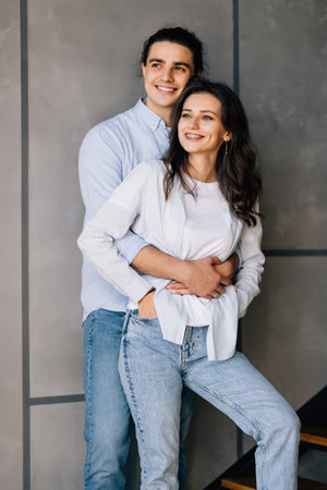 Closeup photo of handsome guy and his pretty lady sitting on stairs in modern interior room