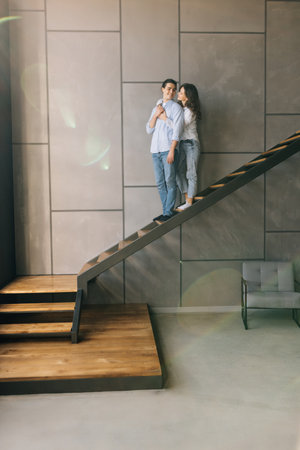 Young couple husband and wife at home sitting on the stairs hugging and smilingの写真素材