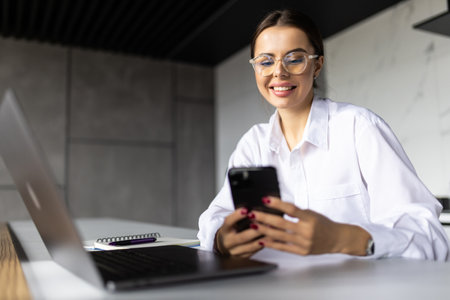 Happy young entrepreneur, business woman using mobile phone at home workplace, chatting, browsing...