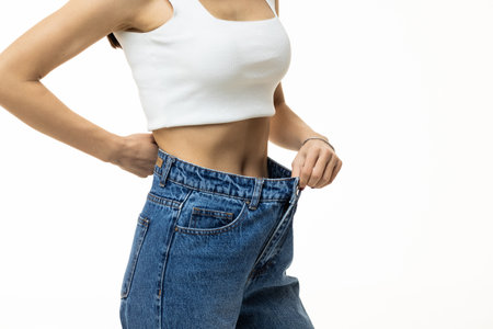 a young athletic girl shows her flat stomach, quickly lost weight and jeans became her big