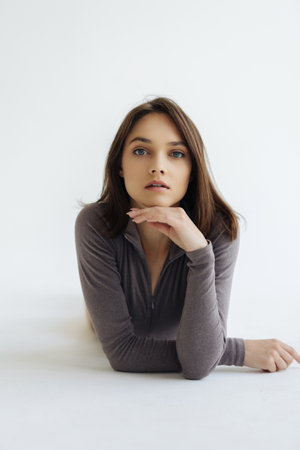 Beautiful girl touching her healthy skin. Photo of young girl sitting on white background. beauty...
