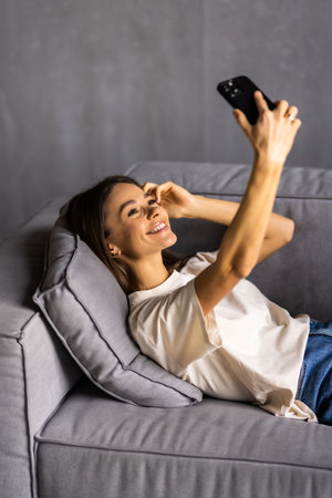 Portrait of a beautiful brunette taking a selfie with her phone at homeの写真素材