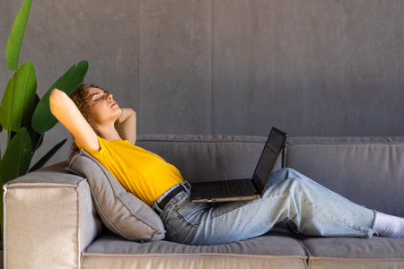 Cozy workplace. Relaxed freelancer girl working with laptop at home, free spaceの写真素材