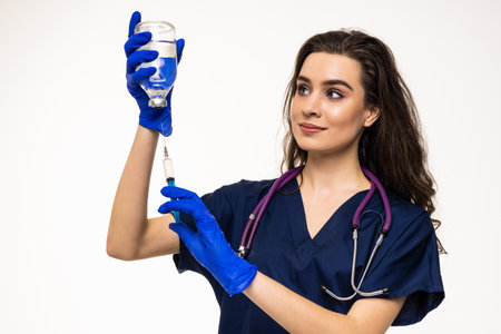Photo of cheerful positive woman doc dressed white coat holding syringe smiling isolated gray color backgroundの写真素材