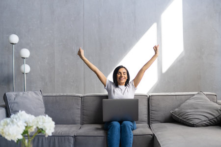 Happy woman with credit card and laptop sitting on sofa at homeの写真素材