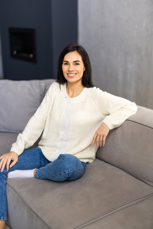 Beautiful woman with laptop resting on couch at homeの写真素材