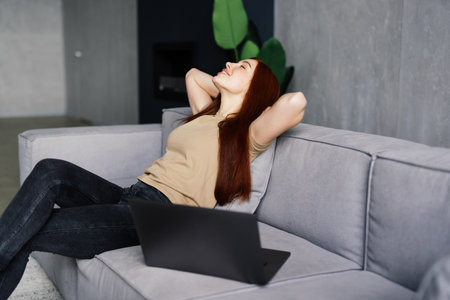 Finally weekends. Millennial girl relaxing at home on couch, enjoying free time, empty spaceの写真素材