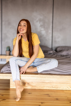 Young beautiful woman sitting on bed at homeの写真素材