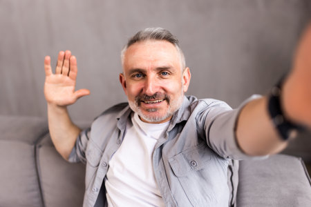 middle-aged man in his sofa takes a picture in selfieの写真素材