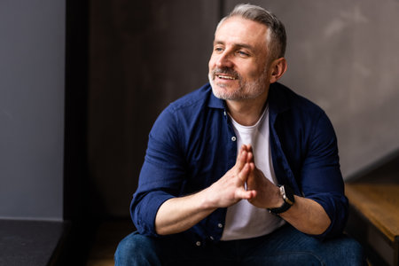 Mature pensive man sitting on stairs at home